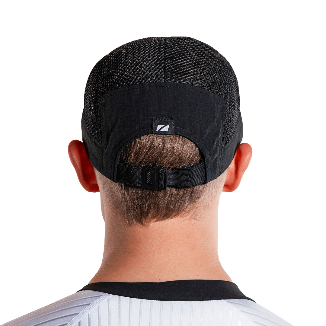 Gorra de malla negra llevada del revés en la cabeza de una persona, con el logotipo de zone3 visible.