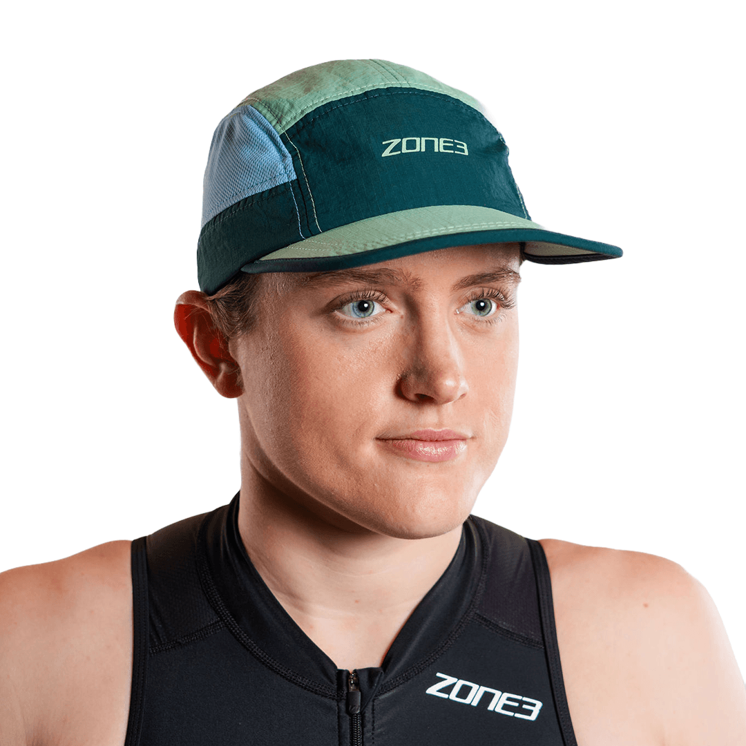 Persona con la gorra de running de 5 paneles en turquesa y el logotipo de zone3, sobre fondo blanco