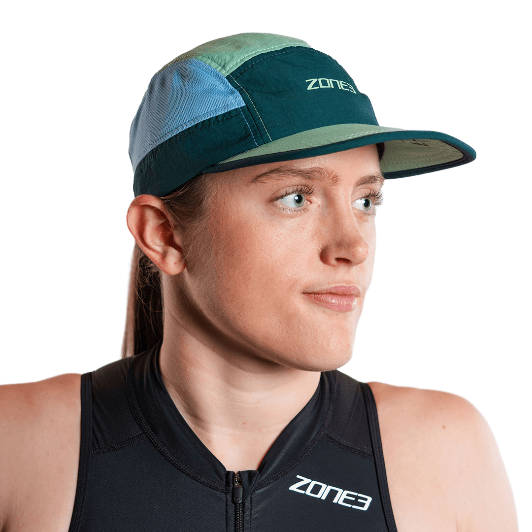 Persona con la gorra de running de 5 paneles en turquesa y el logotipo de zone3, sobre fondo blanco