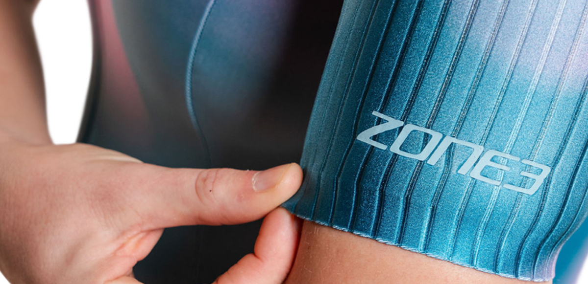 Person wearing blue trisuit with 'Zone3' branding, pointing to the armband.