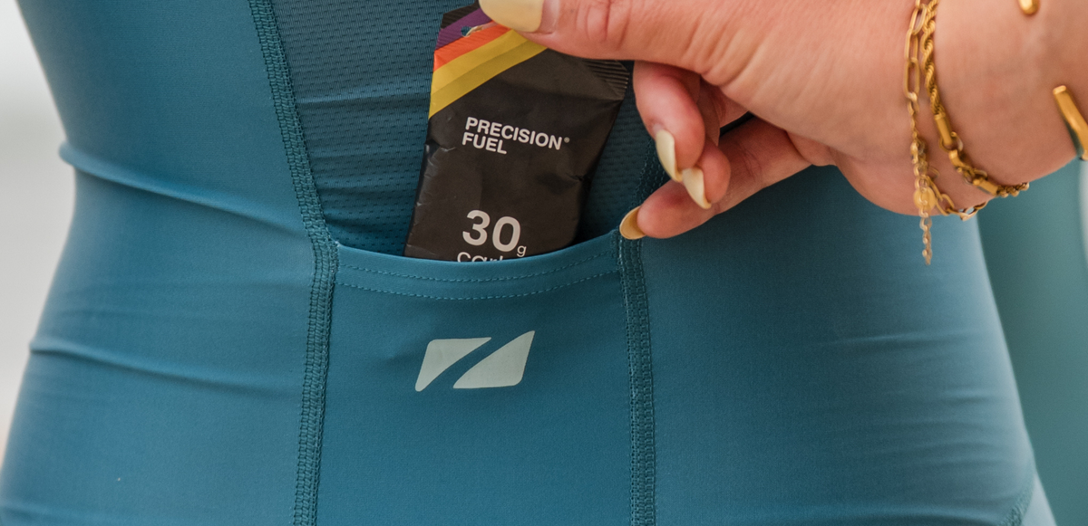 Person wearing teal and pink zone3 trisuit with 'Zone3' branding demonstrating the back pockets