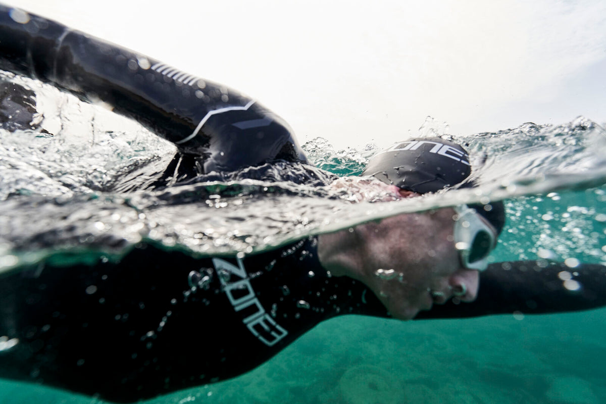 Man Swimming in open water wearing the Agile Wetsuit, swim cap & googles by Zone3