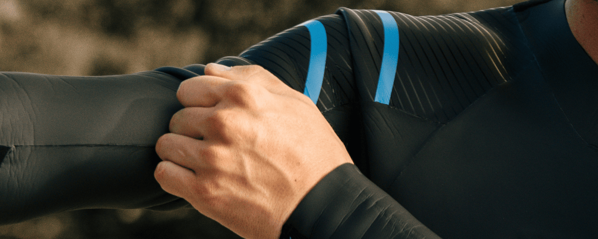 Close-up of a person wearing a black jacket with blue accents, adjusting the sleeve.