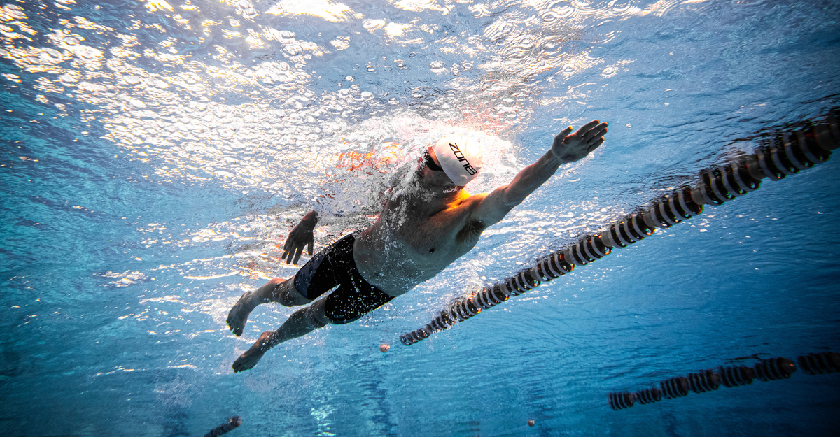 Person swimming underwater in a pool with lane dividers.