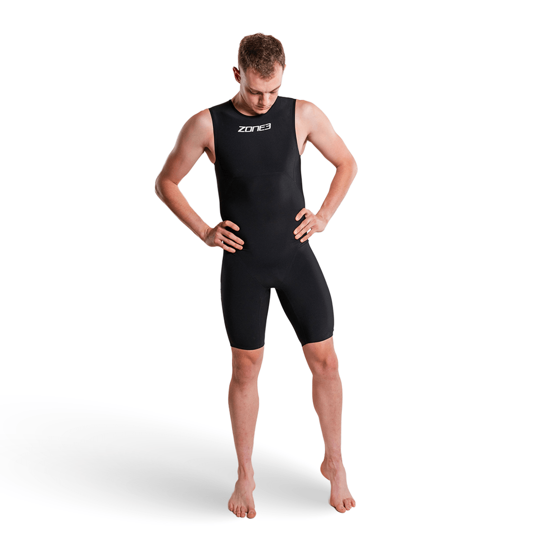 Modelo masculino con el Swimskin Streamline sin mangas de Zone3 en negro, con el logotipo en el pecho, manos en la cintura.