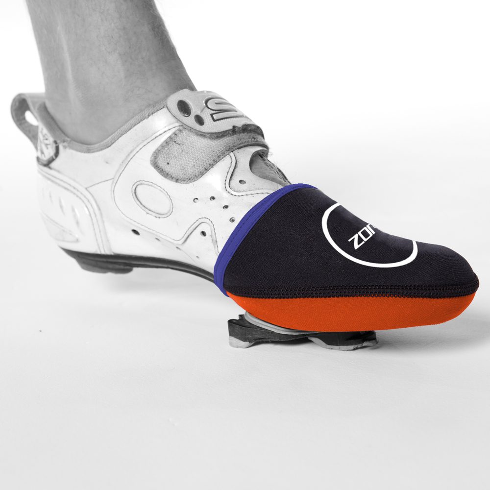 Primer plano de una zapatilla de ciclismo con un cubrepuntas de neopreno en azul y naranja.