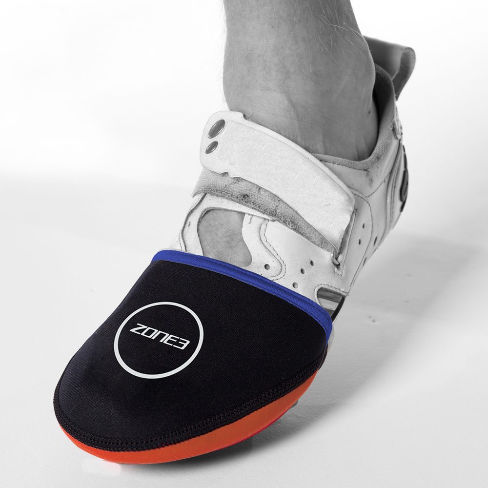 Pie en una zapatilla de ciclismo con un cubrepuntas de neopreno negro y ribete azul