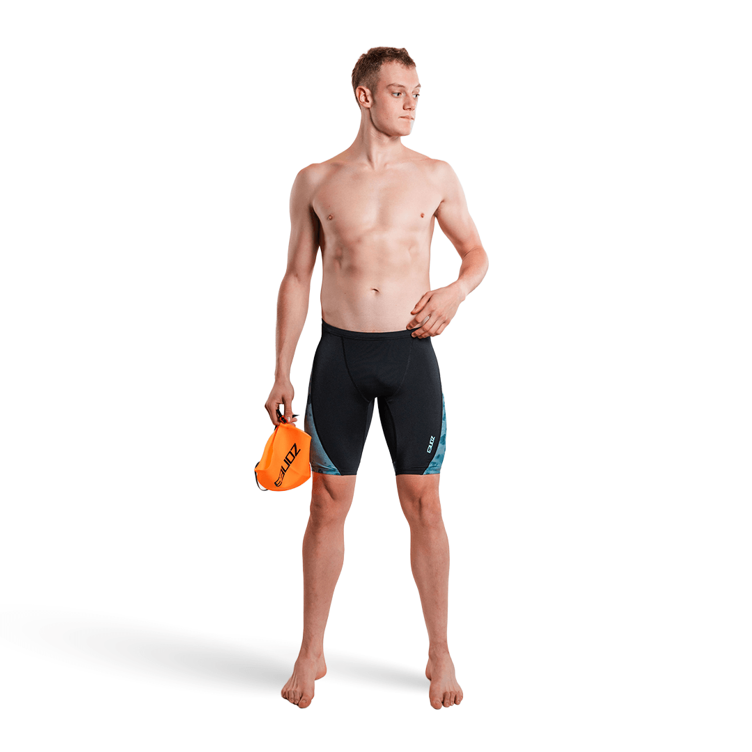 Hombre con el jammer de Zone3 en negro y turquesa, sosteniendo un gorro de natación naranja, sobre fondo blanco